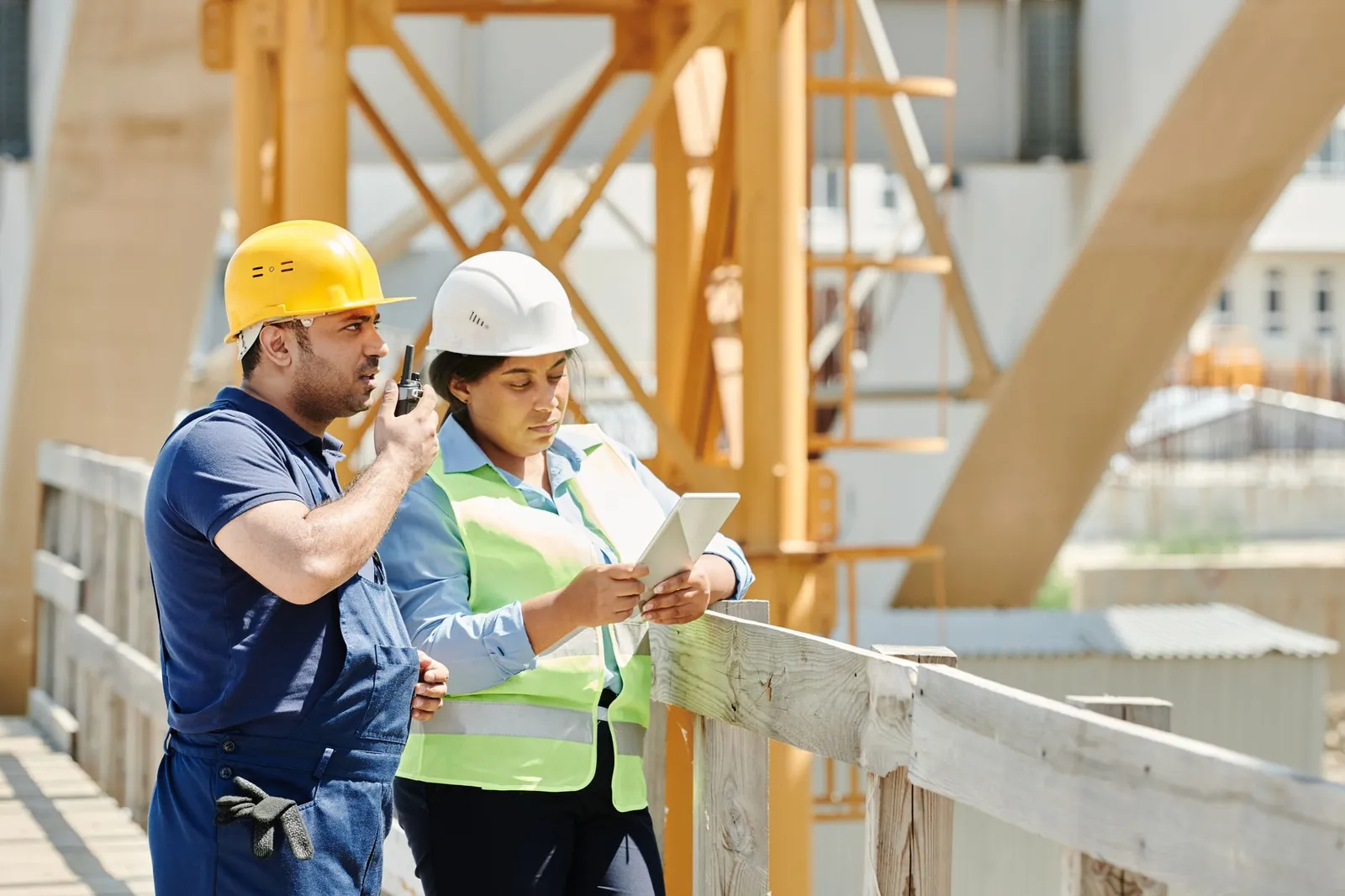 Dos miembros de la cuadrilla en una obra, uno con un radio y otro leyendo una tableta