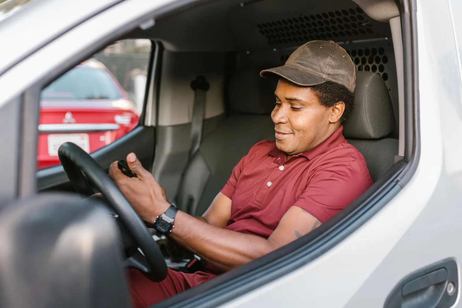 A technician in the driver seat of his van, smiling at his phone